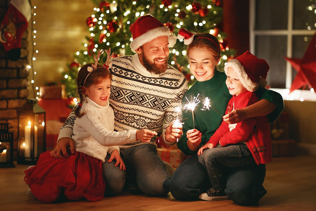 Familie feiert Weihnachten vor dem Tannenbaum