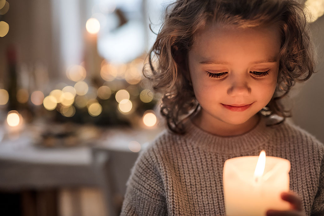 Kind hält eine Kerze in den Händen